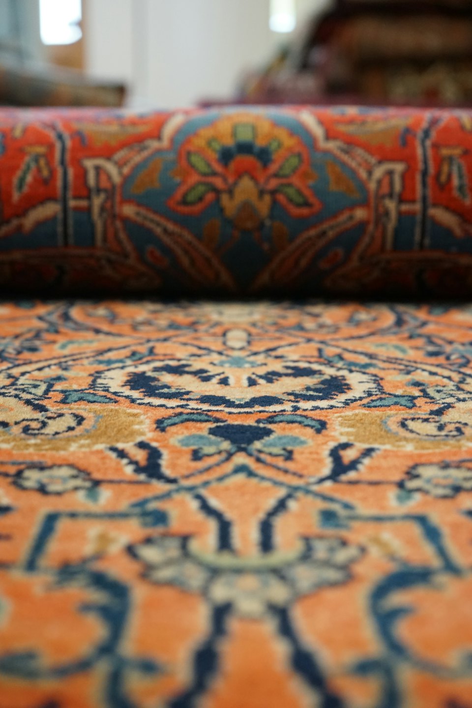 Un tappeto orientale srotolato con intricati motivi arancioni, blu e dorati.